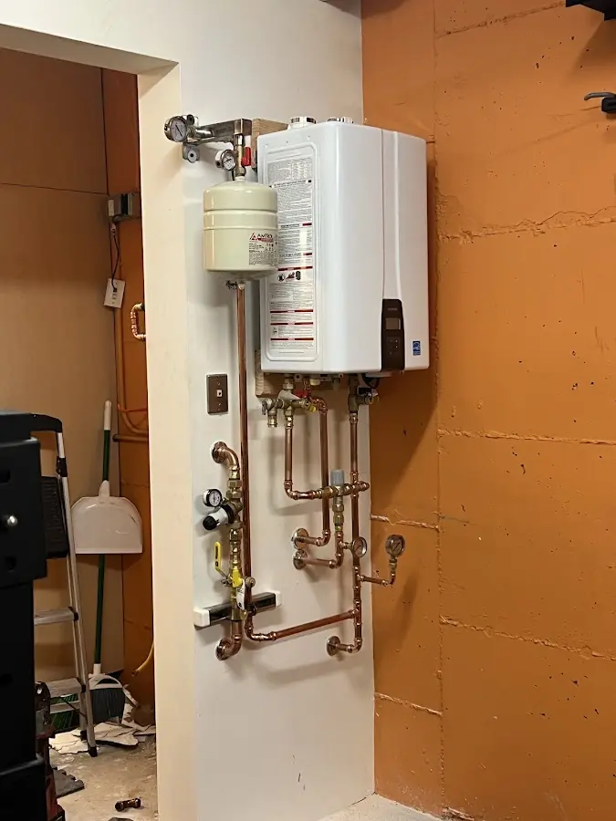 Plumbing technician inspecting water heater connections in Commerce